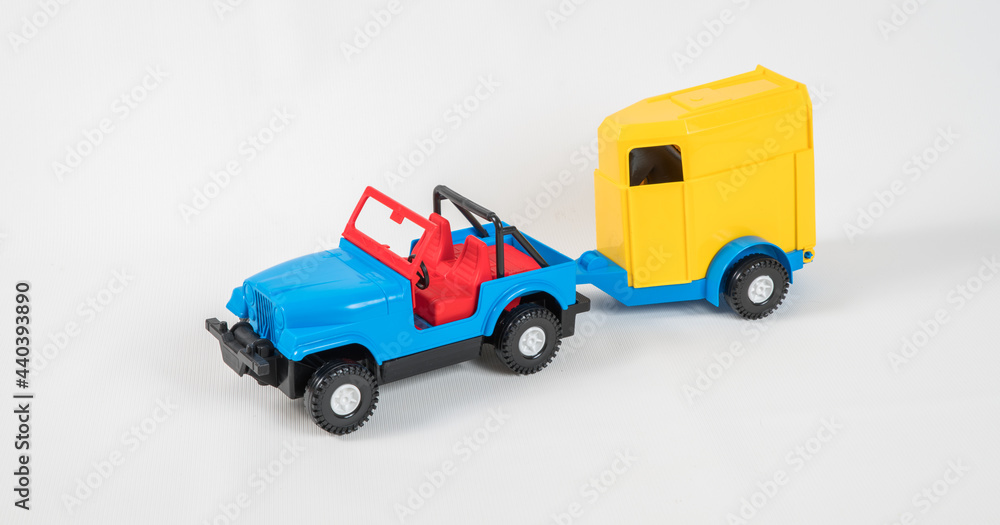Plastic toy multicolored cars isolated on white background. A car with a van for transporting horses.