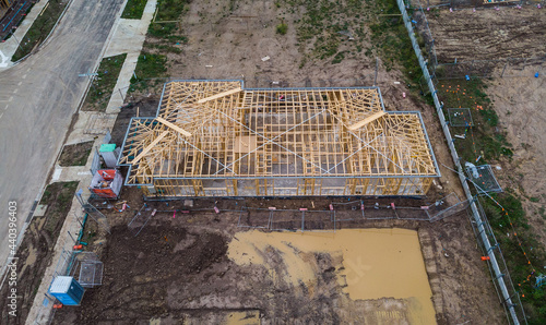A single storey house is being built in a new housing estate in Melbourne Australia, it is still at the frame stage and delayed due to weather, the lot next to it filled with water from recent rain. 