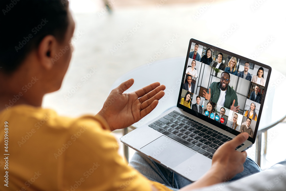 Distant communication using app and laptop. The guy sits on the couch, uses a laptop to communicate with colleagues or friends via video conference, virtual meeting, telecommunication concept Distant communication using app and laptop. The guy sits on the couch, uses a laptop to communicate with colleagues or friends via video conference, virtual meeting, telecommunication concept