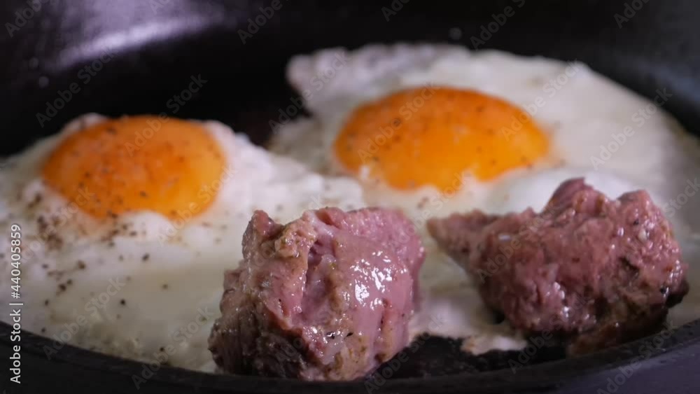 Simple men's food - egg with braised chunks of meat fried in a cast iron skillet Simple men's food - egg with braised chunks of meat fried in a cast iron skillet