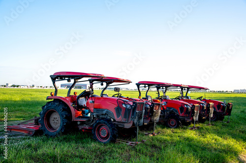Red tractors parking in a grass field with blue sky background. photo