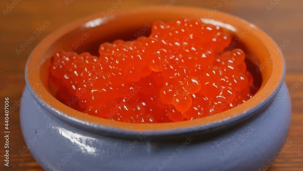red caviar falls into a clay pot blue on the outside and brown on the inside. Plenty of fresh salmon caviar. Close-up. Dolly taking pictures, copy space. red caviar falls into a clay pot blue on the outside and brown on the inside. Plenty of fresh salmon caviar. Close-up. Dolly taking pictures, copy space.