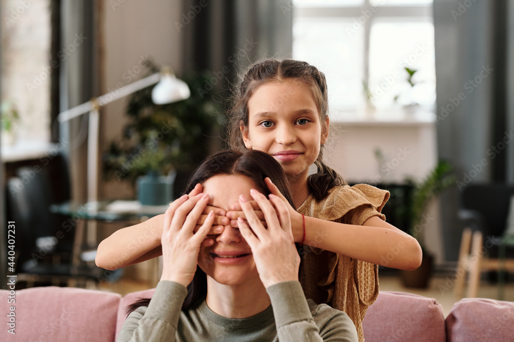 Φωτογραφία Happy cute little girl covering eyes of her smiling mom by hands