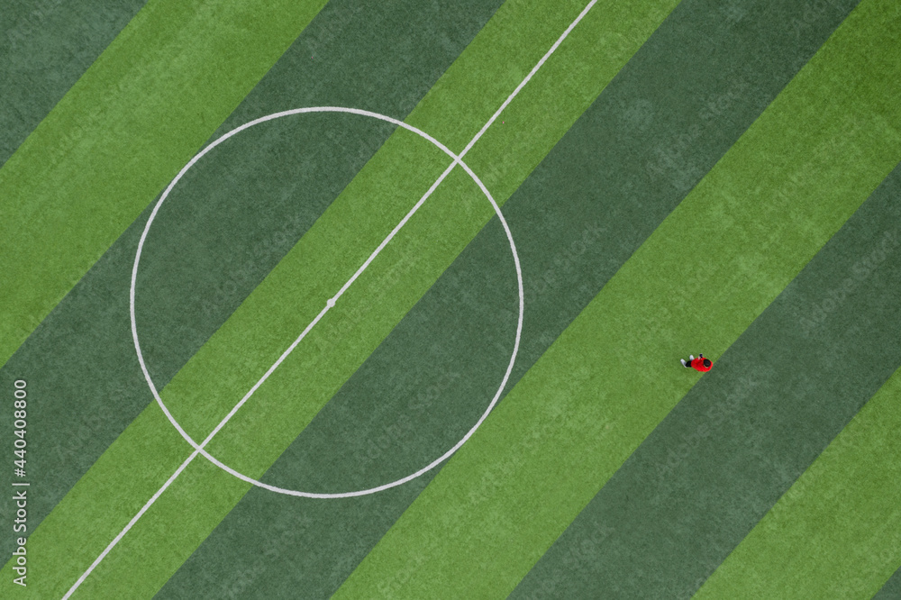 Obraz premium Top view of a person standing on a green lawn in the center of a football field