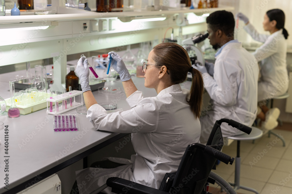 Naklejka premium Group of intercultural lab workers sitting in row during scientific experiments