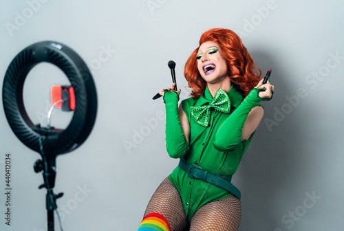 Fotografie Happy drag queen social influencer vlogging online a makeup class with smartphon