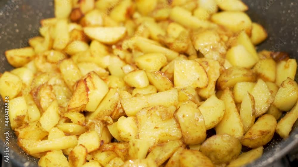 Close-Up Of Frying Village Potatoes. The Potatoes are Steamed and Cooked in a Frying Pan. Delicious Vegetarian Dinner. Vegan Vegetable Food and Diet. Close-Up Of Frying Village Potatoes. The Potatoes are Steamed and Cooked in a Frying Pan. Delicious Vegetarian Dinner. Vegan Vegetable Food and Diet.