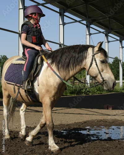 A girl during horseback riding lesson. Portret outside, sunny day.