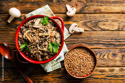 Bilde på lerret buckwheat porridge with fried mushrooms in a ceramic pot on a white wooden backg