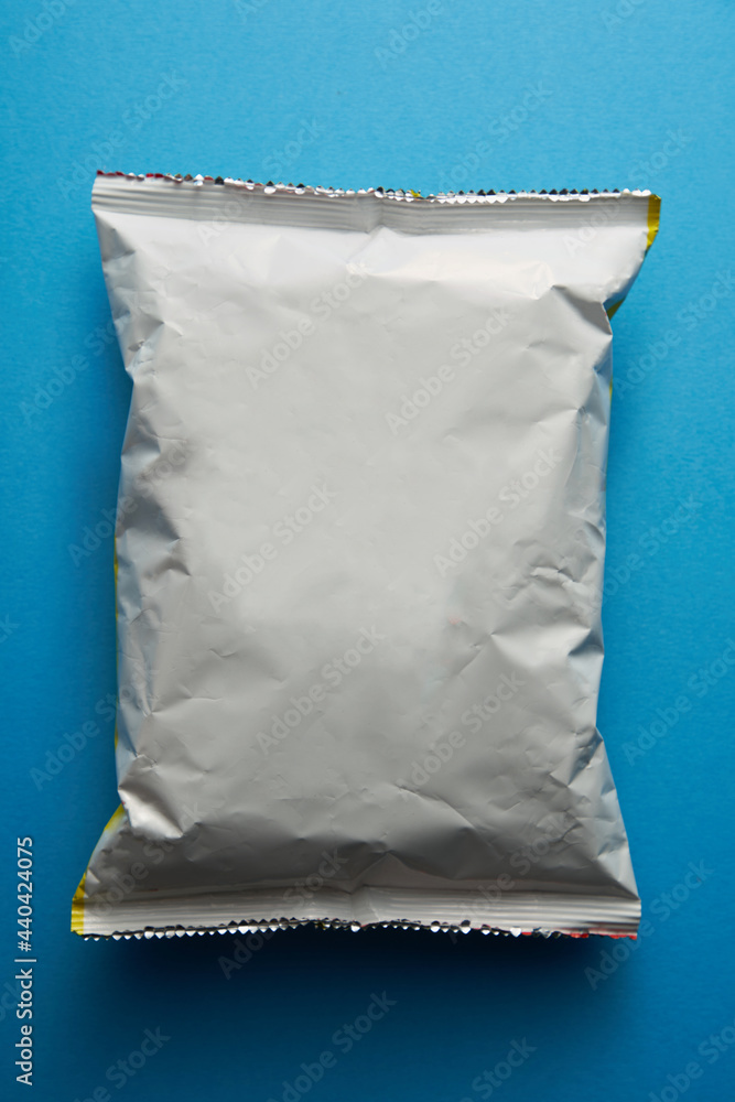 Top view of blank plastic pouch snack packaging on blue background