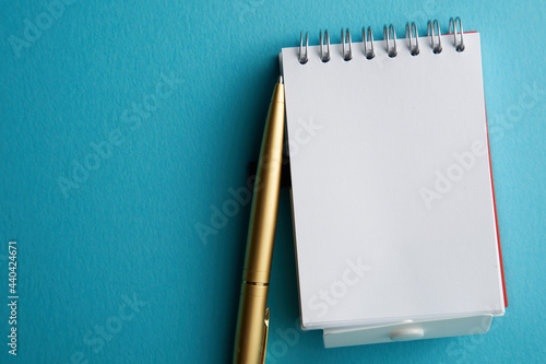 blank note pad with pen on blue background