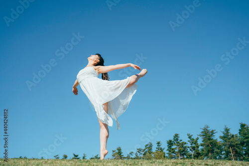 空と白いワンピースの踊る女性（ジャンプ） 
