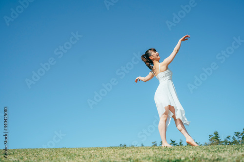  空と白いワンピースの踊る女性