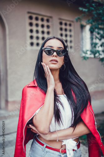 Beautiful young woman posing in front of apartment building dressed casually