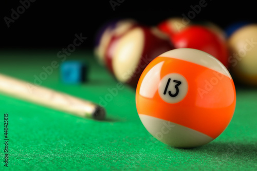 Billiard ball with number 13 on green table, closeup. Space for text photo