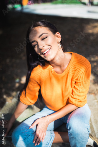 Glamour portrait of a young and beautiful woman sitting in the park. Autumn season