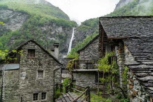 the famous village of Foroglio in Ticino, Switzerland. With the houses built by rocks and the waterfall in the background on a rainy day in May photo