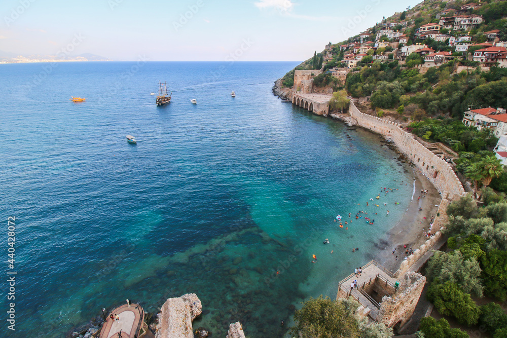 The historical Kızıl Kule (Red Tower), castle wall and ruins of the historic harbor of Alanya beach, Top view to the shipyard and mediterranean sea.