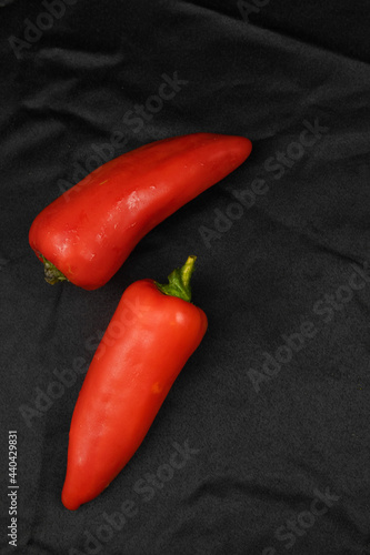 Red bell pepper on a black background. Black fabric background in folds.