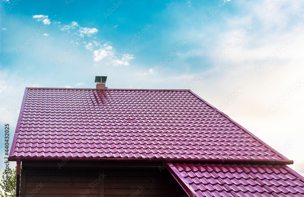 Roof of a house with a red tile roof under a clear blue sky in summer.