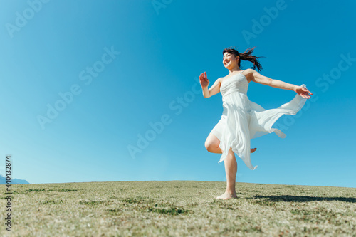 空と白いワンピースの走る女性 