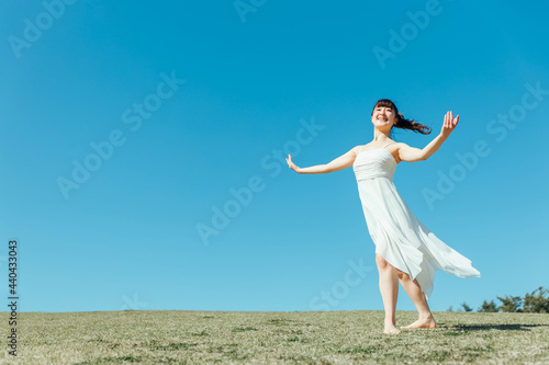 空と白いワンピースの踊る女性 