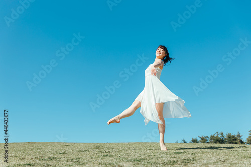 空と白いワンピースの踊る女性 