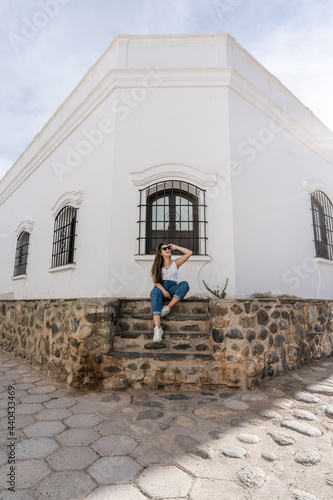 young hispanic woman sitting outside a colonial house in Argentina © Marcos Reppetti