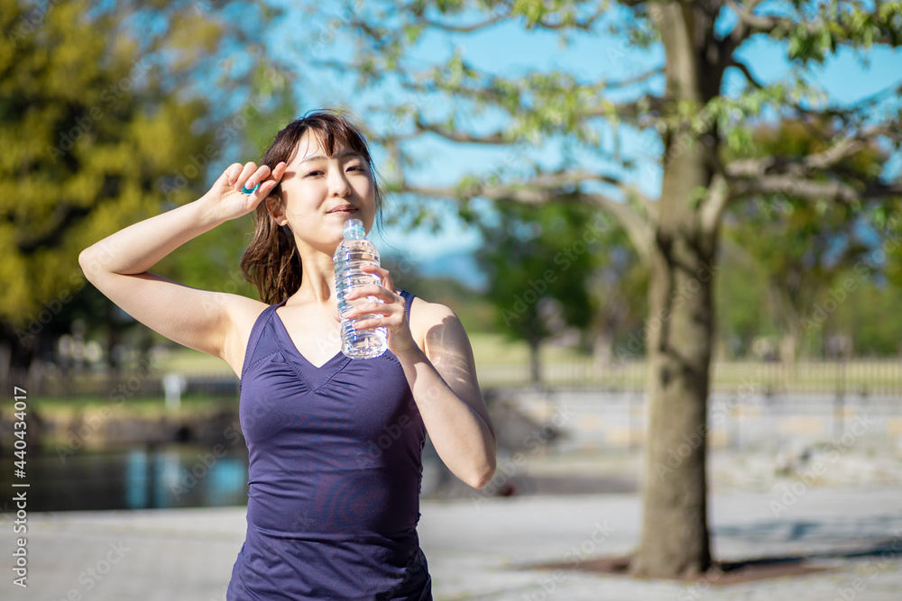 公園でトレーニングする女性（水を飲む）
