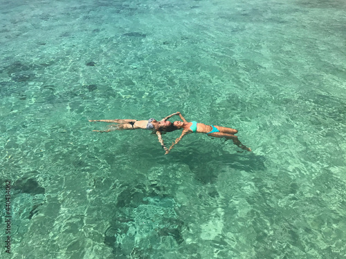 Beach travel. Girls floating and swimming in the crystal sea water. Caribbean Sea
