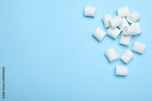 Delicious puffy marshmallows on light blue background, flat lay. Space for text