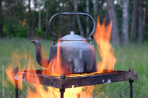 An old metal kettle stands amid the flames of the fire