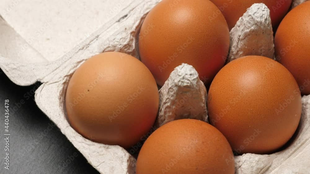 Uncooked eggs in pack. Rotating on black slate background. Closeup Uncooked eggs in pack. Rotating on black slate background. Closeup