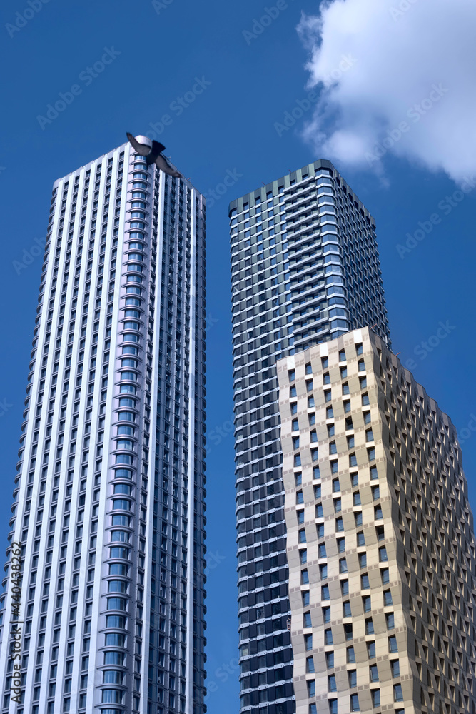 Fototapeta premium Two modern tall buildings, skyscrapers in the blue sky.