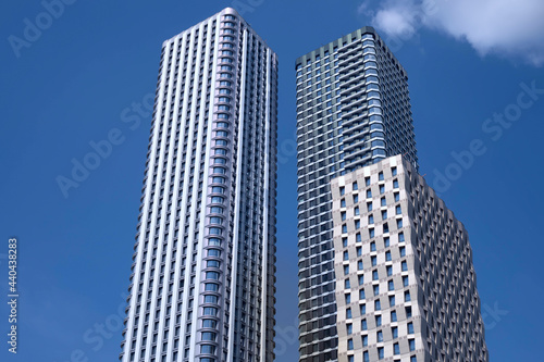 Two modern tall buildings, skyscrapers in the blue sky.