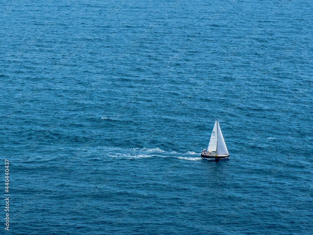 A sailboat sails the Mediterranean near the Nao Cape in Javea, Spain