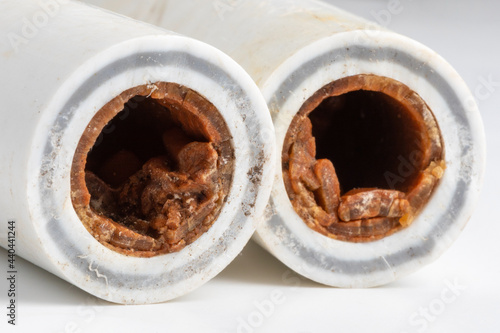 Old broken sludge plumbing polypropylene pipes with red rust and limescale. Corrosion, sludge and hard water concept photo