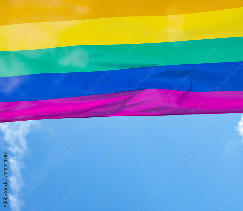 Rainbow flag in sunshine against blue sky