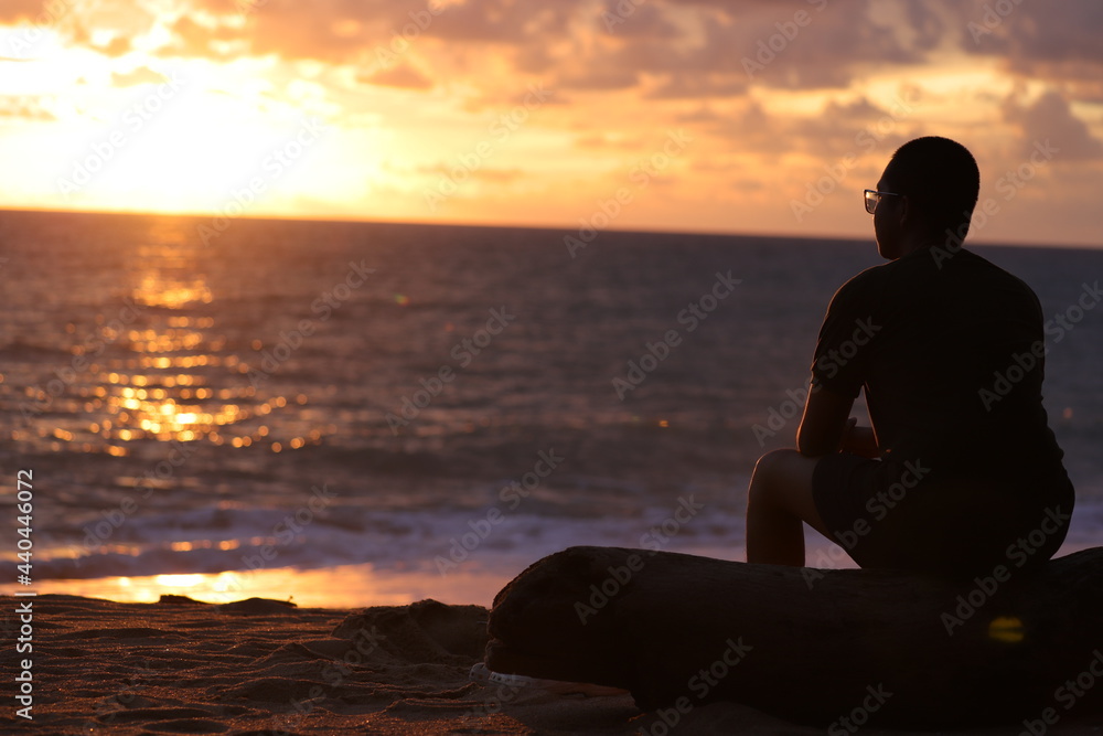 Nature and beauty concept. Orange sundown. silhouette at sunset.Young man sitting outdoors watching the sunset. Thinking and relaxing concept.man sit on a bench on a relax in nature sunset.