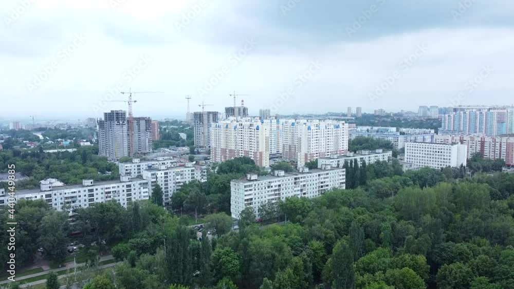Modern city. Green trees and tall stone houses. Tower construction cranes. Cloudy sky. Developing city. Video of the city from a drone. Modern city. Green trees and tall stone houses. Tower construction cranes. Cloudy sky. Developing city. Video of the city from a drone.