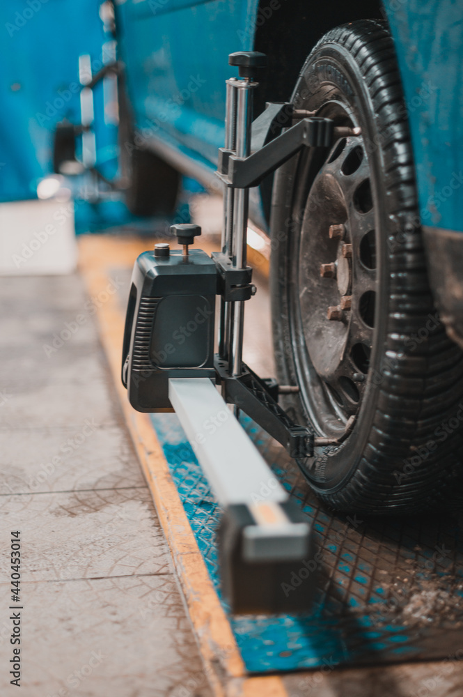 Fototapeta premium Close-up of a tire clamped by a leveler that passes the automatic alignment of the wheels in the garage, garage and tools for the mechanic.