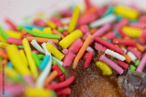 Pastries concept. Donuts with chocolate glaze with colorfull sprinkles, on a pink plate. Macro