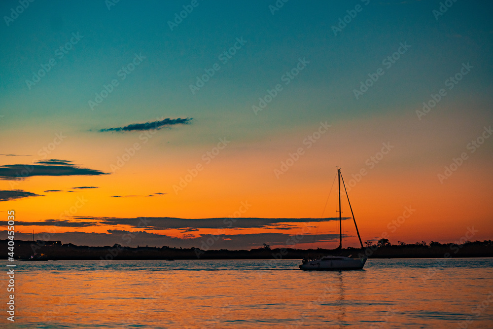 Sailboat sailing in the sea with a beautiful and colorful sunset. Paraná, Entre Ríos, Argentina. Sailboat sailing in the sea with a beautiful and colorful sunset. Paraná, Entre Ríos, Argentina.