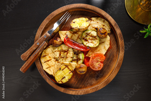 set of baked vegetables zucchini tomato potatoes bell pepper on wooden plate
