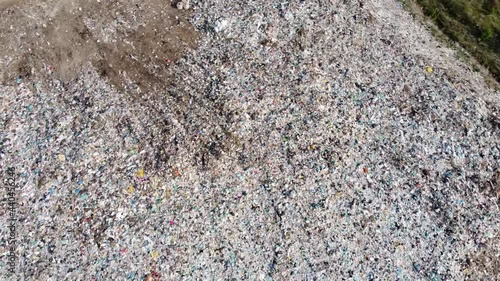 Large city trash can. Waste disposal site. An old tractor pushes a lot of debris. A huge pile of rubbish. The video was filmed from a drone.