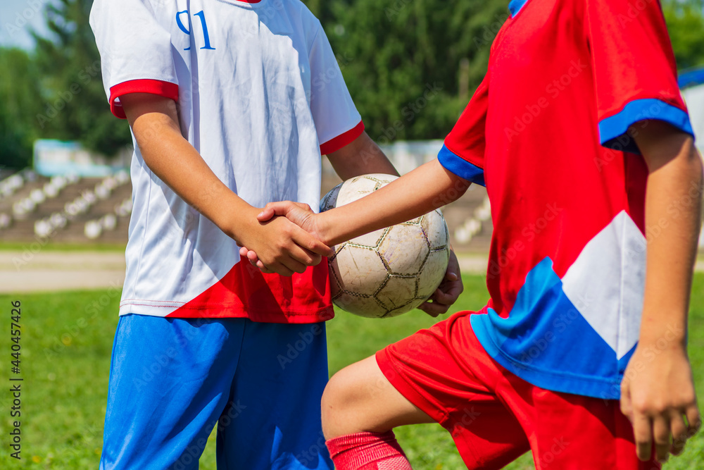 A close-up of the cut off arms of two young footballers. Handshake before the start of the match. A close-up of the cut off arms of two young footballers. Handshake before the start of the match.