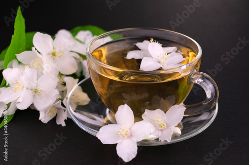 Jasmine tea in a transparent cup on a black background.