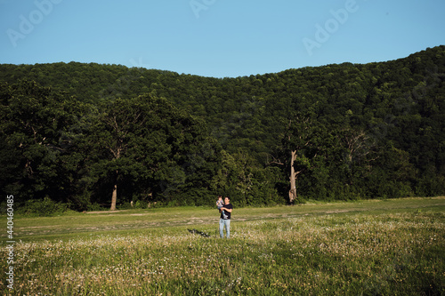 Young family spends a fun time in nature in the park. Father and son in chamomile field at sunset. A man holding a child in his arms smiles and has fun.