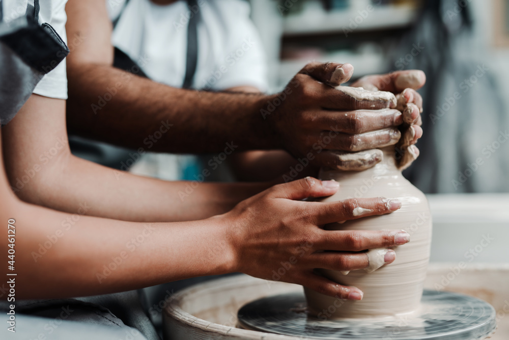 Photo near and side. Male and female hands make a vase of clay. Date in the workshop Photo near and side. Male and female hands make a vase of clay. Date in the workshop