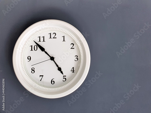 A white round clock on a gray background. Space for the text. Copy space